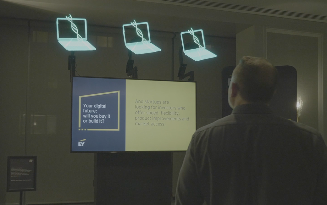 A man looking at a display with three holograms connected above it